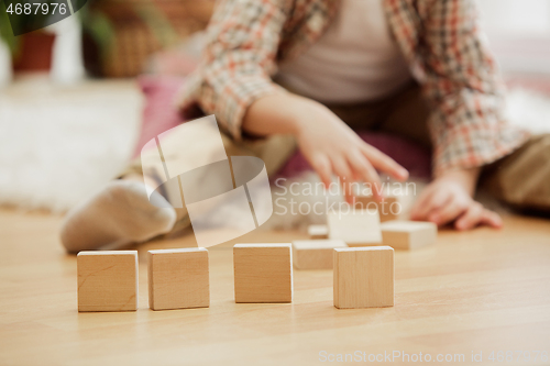 Image of Little child sitting on the floor. Pretty boy palying with wooden cubes at home