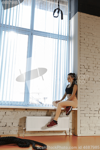 Image of Relaxing after training. Beautiful young woman looking away while sitting at gym
