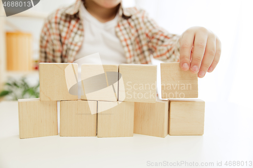 Image of Little child sitting on the floor. Pretty boy palying with wooden cubes at home