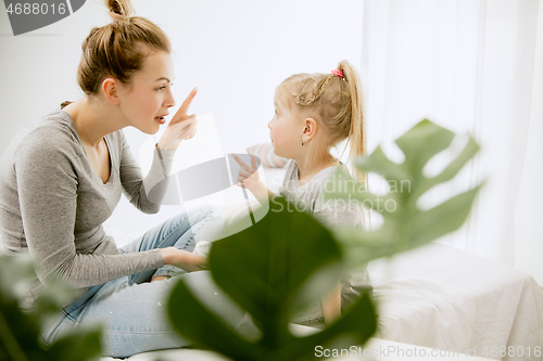 Image of Young mother and her little daughter hugging and kissing on bed