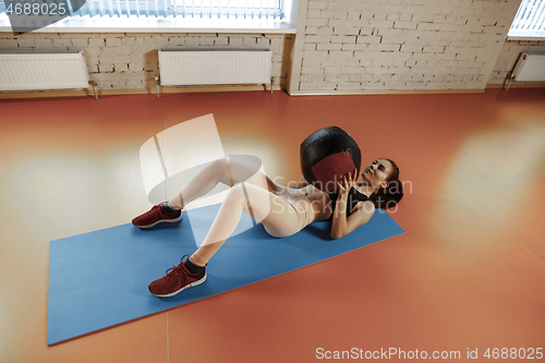 Image of Beautiful slim brunette doing some gymnastics at the gym