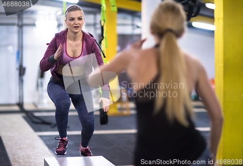 Image of athletes working out  jumping on fit box