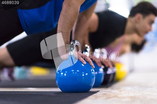 Image of young athletes doing pushups with kettlebells