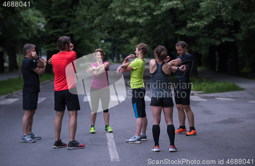 Image of runners team warming up and stretching before morning training