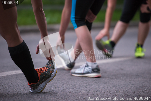 Image of runners team warming up and stretching before morning training