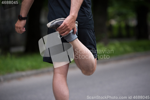 Image of male runner warming up and stretching before morning training