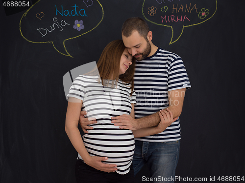 Image of pregnant couple posing against black chalk drawing board