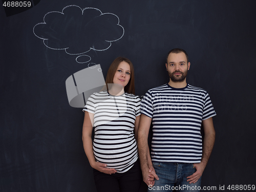 Image of pregnant couple posing against black chalk drawing board