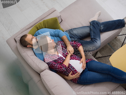 Image of pregnant couple relaxing on sofa