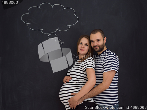 Image of pregnant couple posing against black chalk drawing board