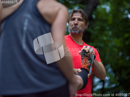 Image of runners team warming up and stretching before morning training