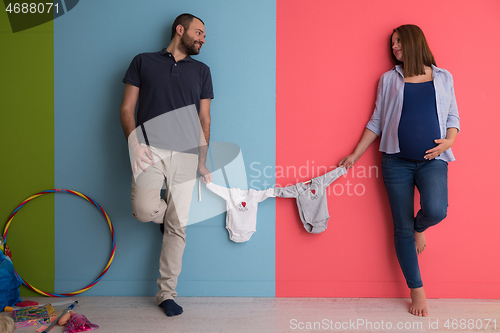 Image of young couple holding baby bodysuits