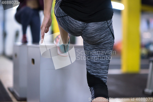 Image of athletes working out  jumping on fit box