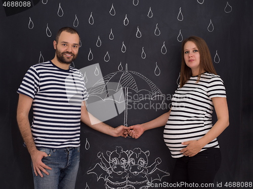 Image of pregnant couple drawing their imaginations on chalk board