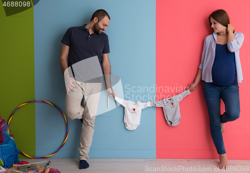 Image of young couple holding baby bodysuits