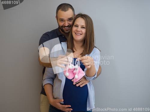 Image of pregnant couple holding newborn baby shoes