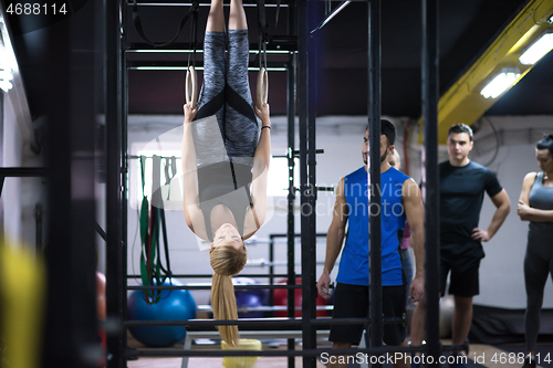 Image of woman working out with personal trainer on gymnastic rings