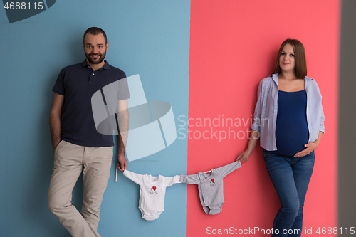 Image of young couple holding baby bodysuits