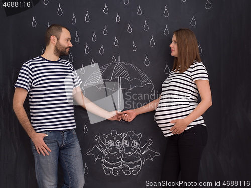 Image of pregnant couple drawing their imaginations on chalk board