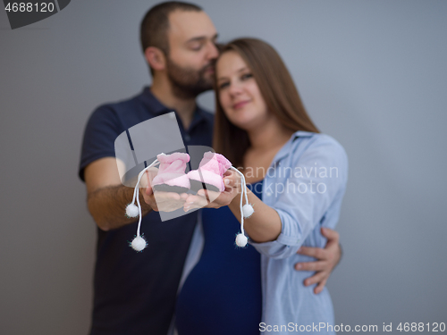 Image of pregnant couple holding newborn baby shoes