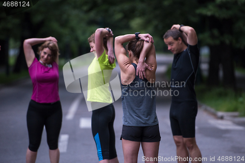 Image of runners team warming up and stretching before morning training