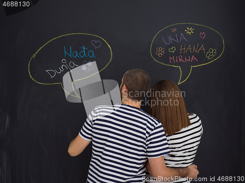 Image of pregnant couple writing on a black chalkboard