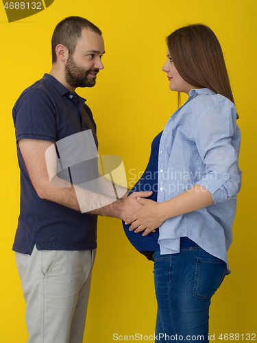 Image of pregnant couple  isolated over yellow background