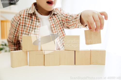 Image of Little child sitting on the floor. Pretty boy palying with wooden cubes at home