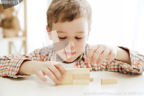 Image of Little child sitting on the floor. Pretty boy palying with wooden cubes at home