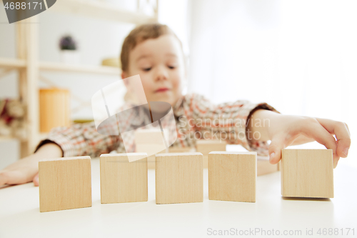 Image of Little child sitting on the floor. Pretty boy palying with wooden cubes at home