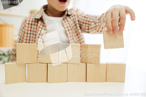 Image of Little child sitting on the floor. Pretty boy palying with wooden cubes at home