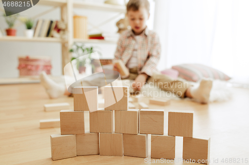 Image of Little child sitting on the floor. Pretty boy palying with wooden cubes at home