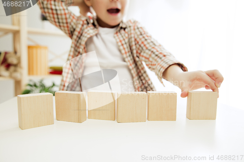 Image of Little child sitting on the floor. Pretty boy palying with wooden cubes at home