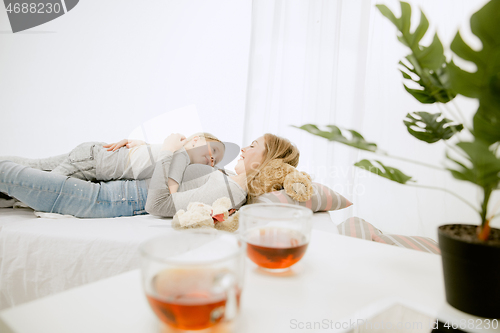 Image of Young mother and her little daughter hugging and kissing on bed