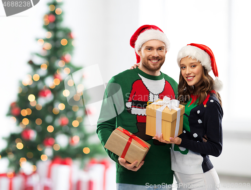 Image of happy couple in sweaters with christmas gifts