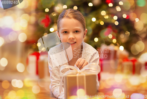 Image of smiling girl with christmas gift at home