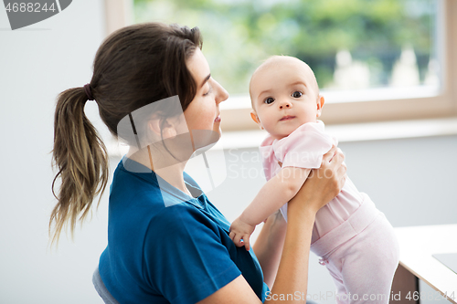 Image of mother holding baby daughter at home