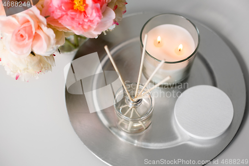 Image of aroma reed diffuser, candle and flowers on table