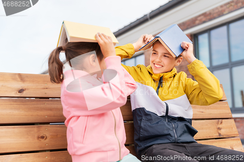 Image of school children with books having fun outdoors