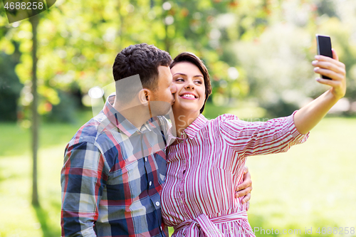 Image of happy couple in park taking selfie by smartphone