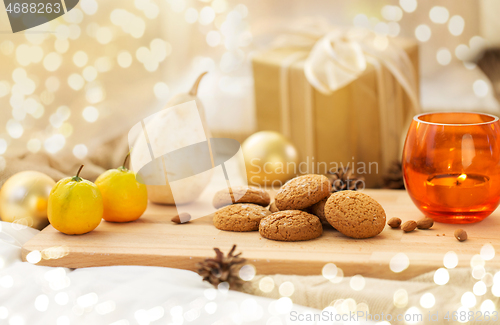 Image of cookies, lemon, candle and christmas gift at home