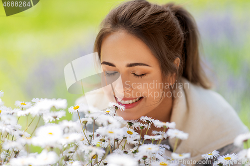 Image of close up of woman smelling chamomile flowers