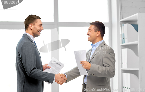 Image of happy businessmen making handshake at office