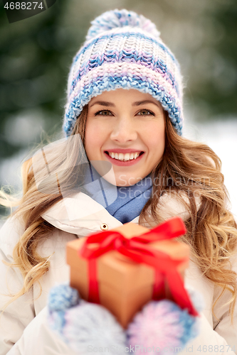 Image of happy young woman with christmas gift in winter