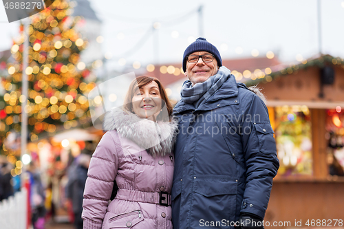 Image of happy senior couple hugging at christmas market