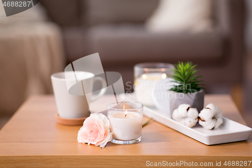 Image of burning candle and flower bunch on wooden table