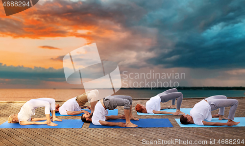 Image of group of people making yoga exercises outdoors