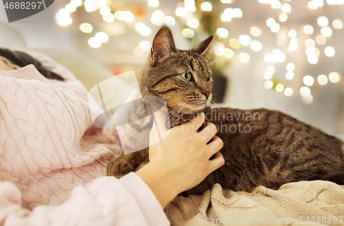 Image of close up of owner with tabby cat in bed at home