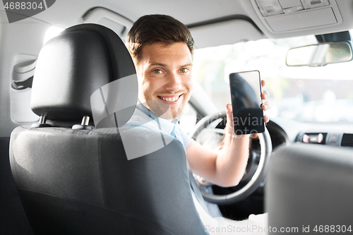 Image of man or car driver showing smartphone