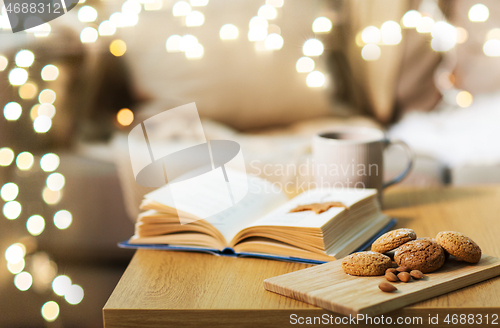 Image of oat cookies, almonds and book on table at home